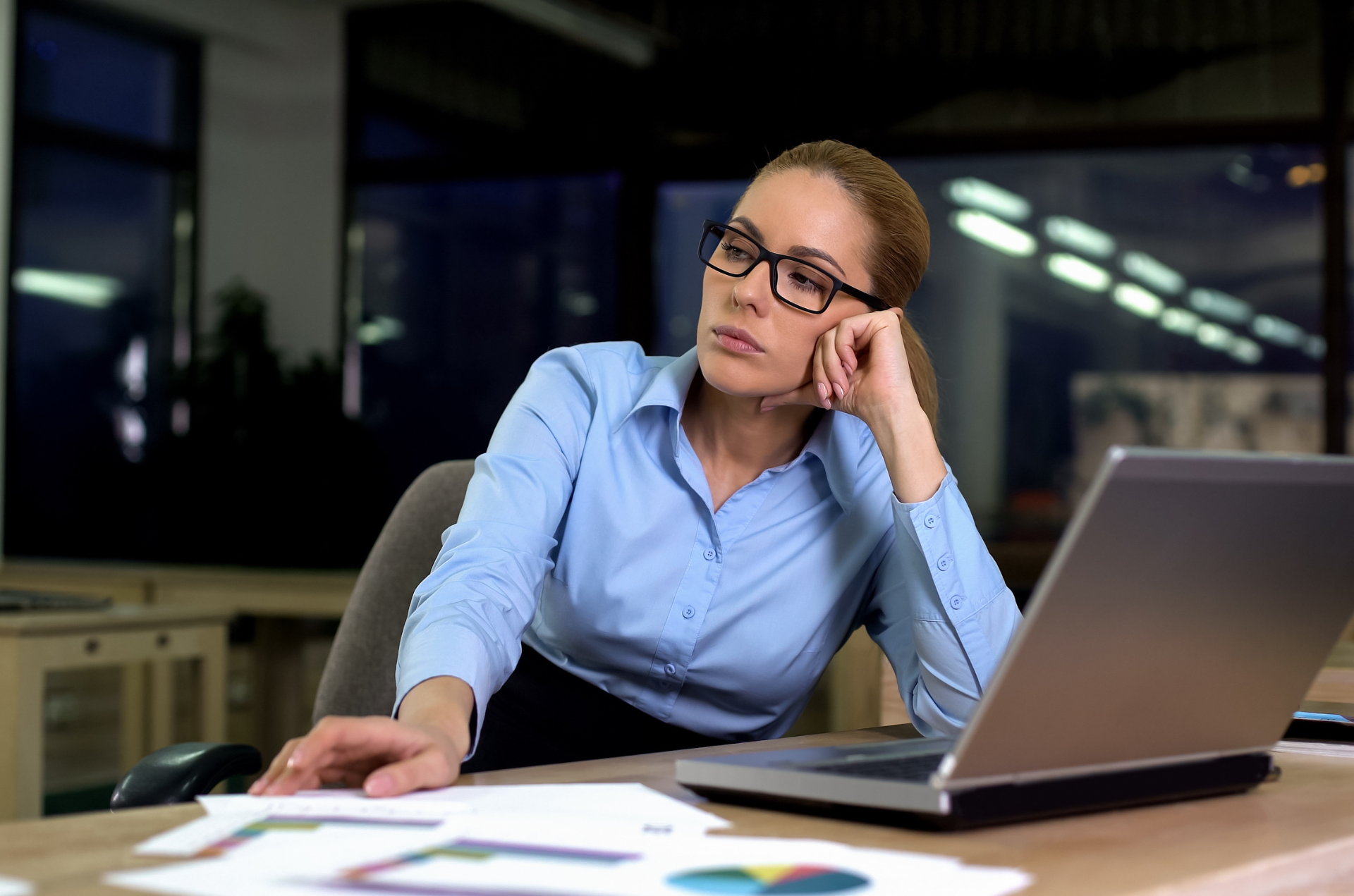 Mujer reflexionando en su puesto de trabajo frente al ordenador, ilustrando la insatisfacción laboral